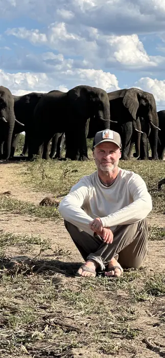 Gonzalo Prieto sentado frente a una manada de elefantes en África